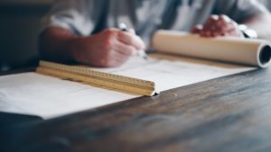 Minimalist designer working at his desk with a pen, paper and ruler.
