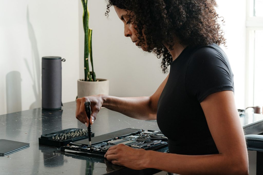 Featured image for an article covering most repair-friendly personal technology, including repairable phones, laptops and more. This image features a woman repairing her laptop.