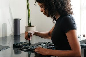 Featured image for an article covering most repair-friendly personal technology, including repairable phones, laptops and more. This image features a woman repairing her laptop.